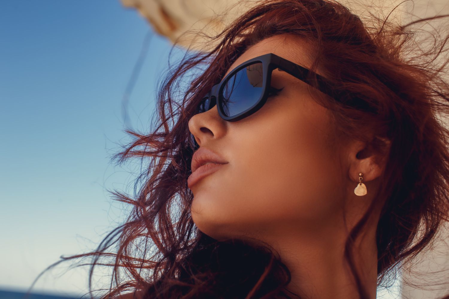 A close up of a woman wearing sunglasses and earrings.