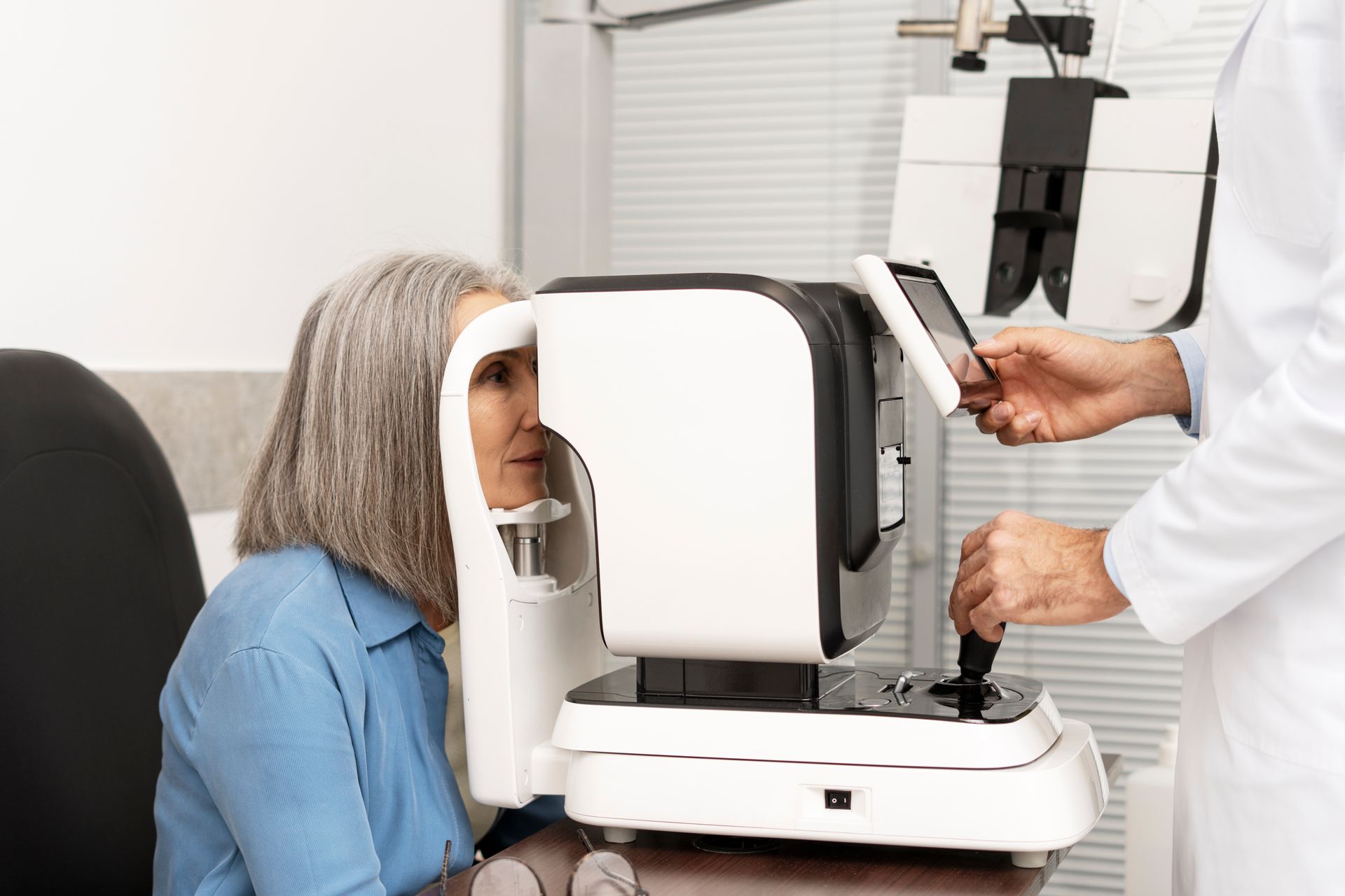 Woman undergoing eye exam with a machine; doctor operates controls.