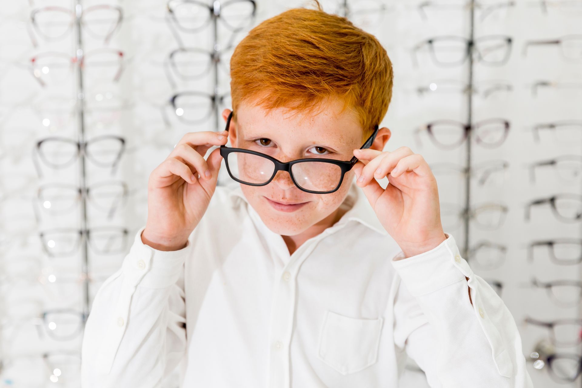 A young boy is trying on glasses in an optical store.