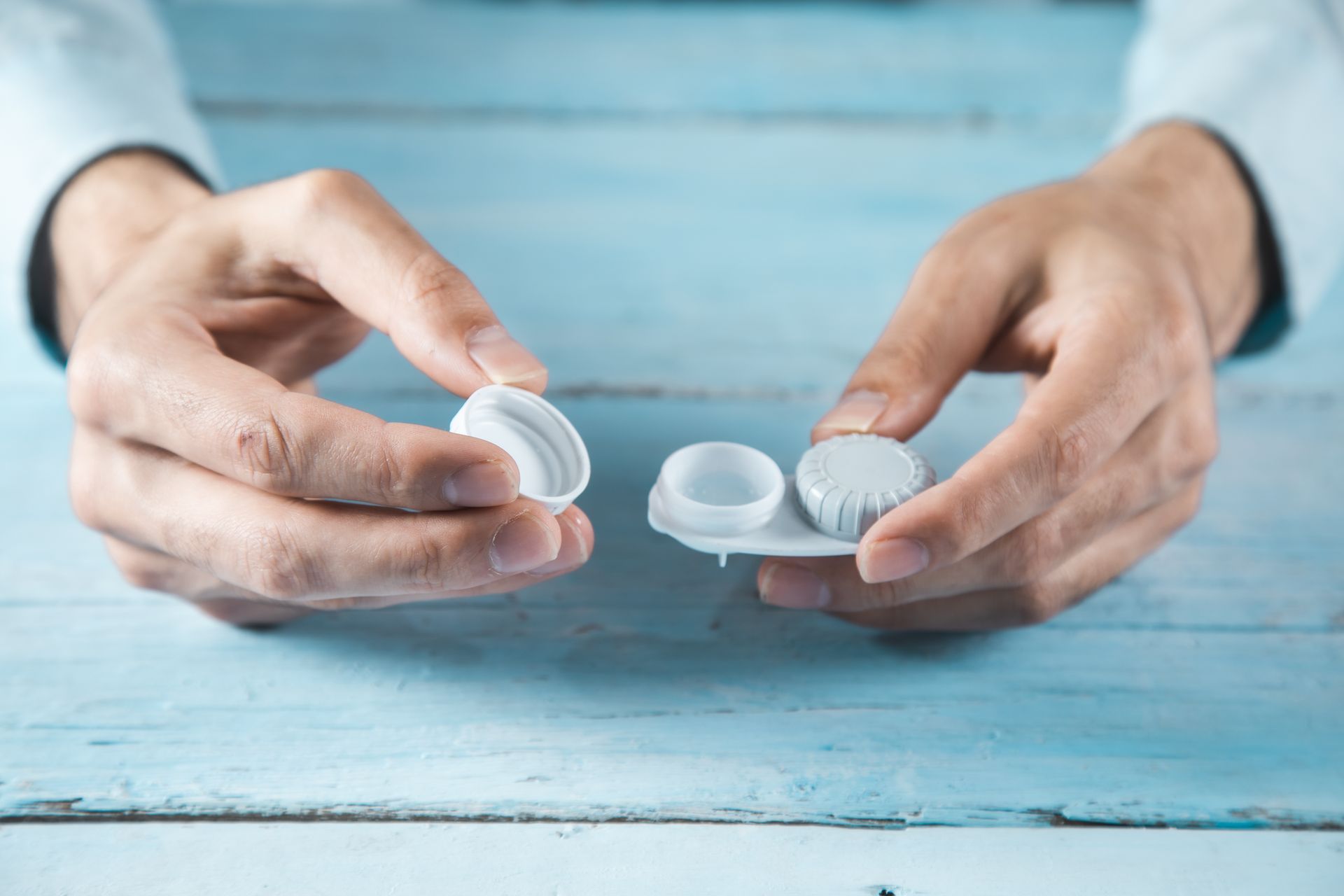 A person is holding a contact lens case in their hands.