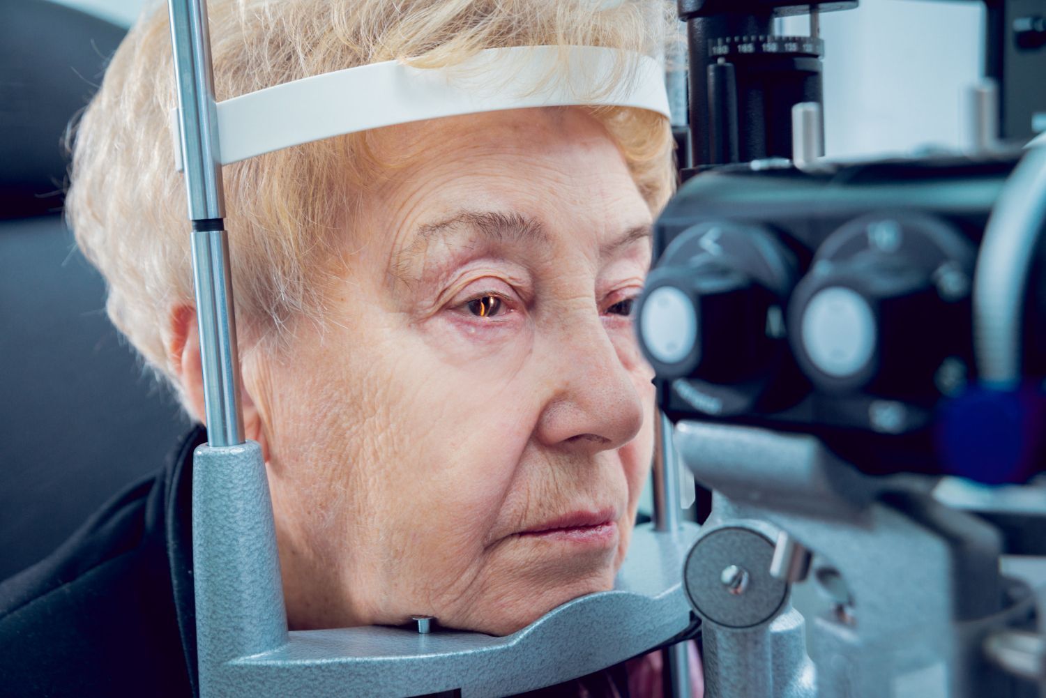 An elderly woman is getting her eyes examined by an ophthalmologist.