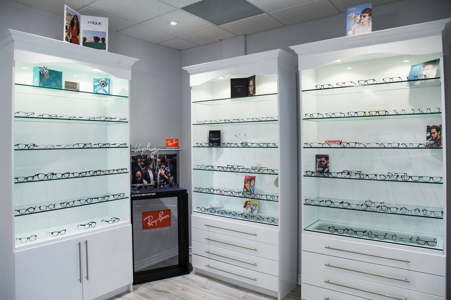 A woman is helping a man try on glasses in an optical shop.