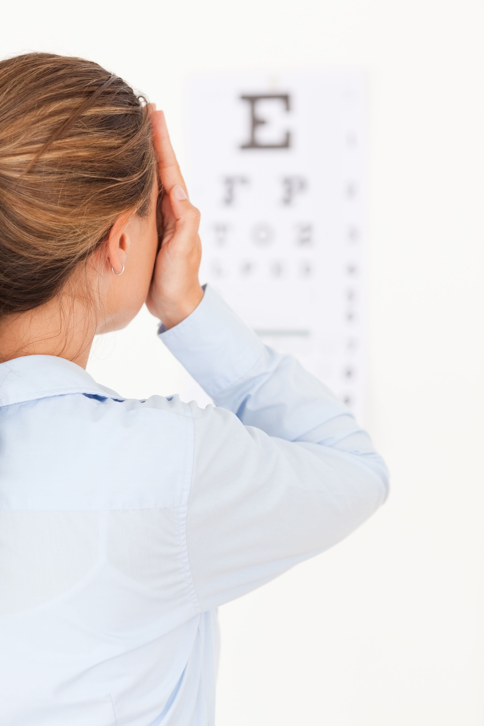 A woman is looking at an eye test chart.