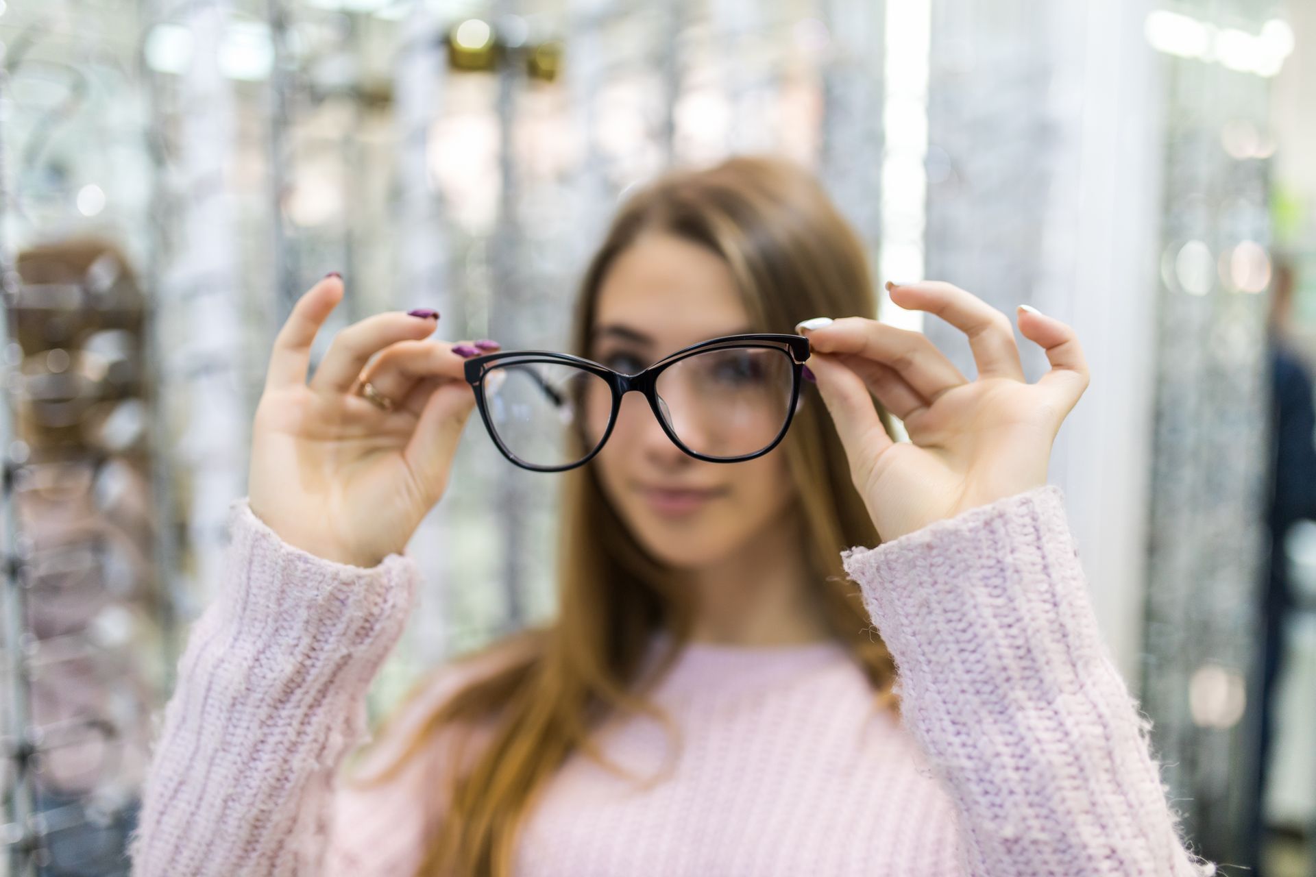 A woman is holding a pair of glasses in front of her face.