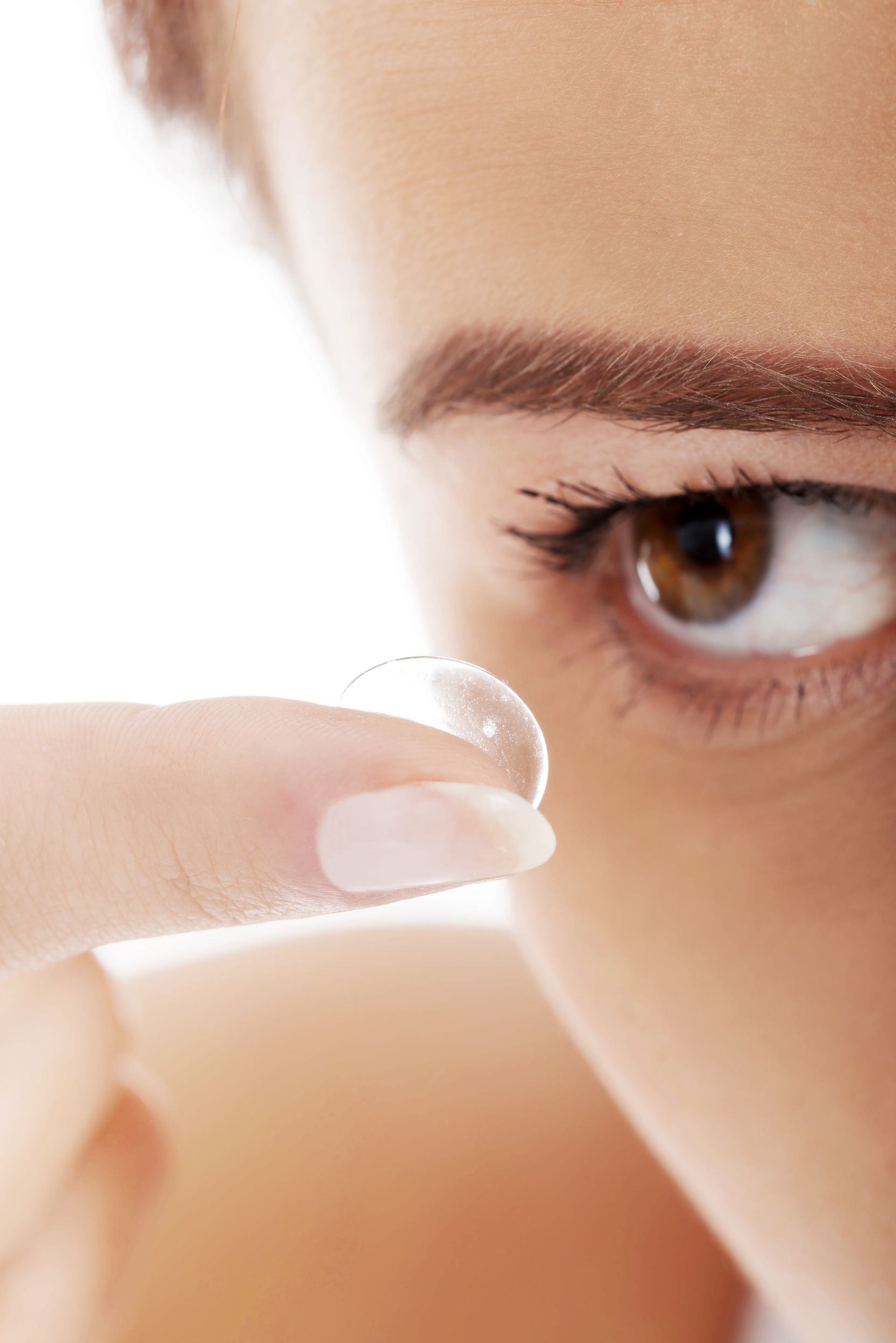 A woman is putting a contact lens in her eye.