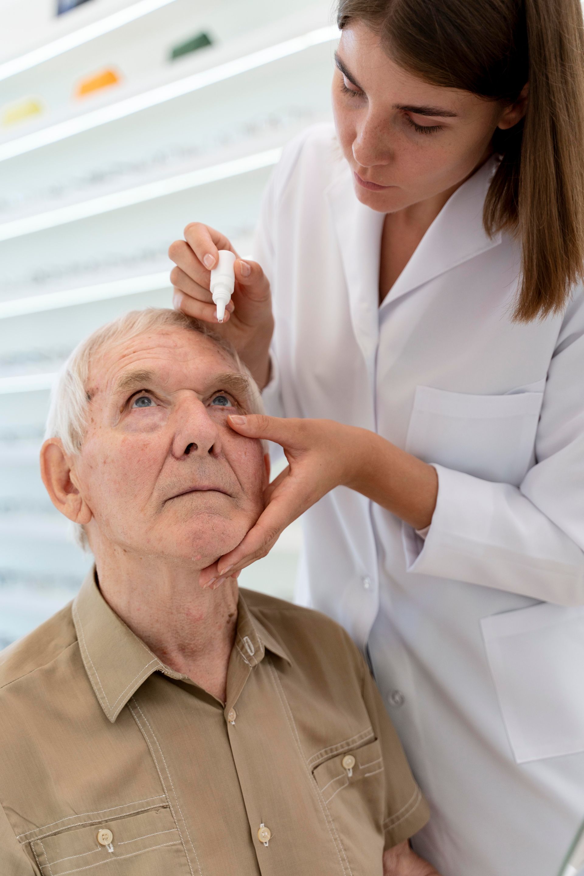 A nurse is applying eye drops to an elderly man 's eye.