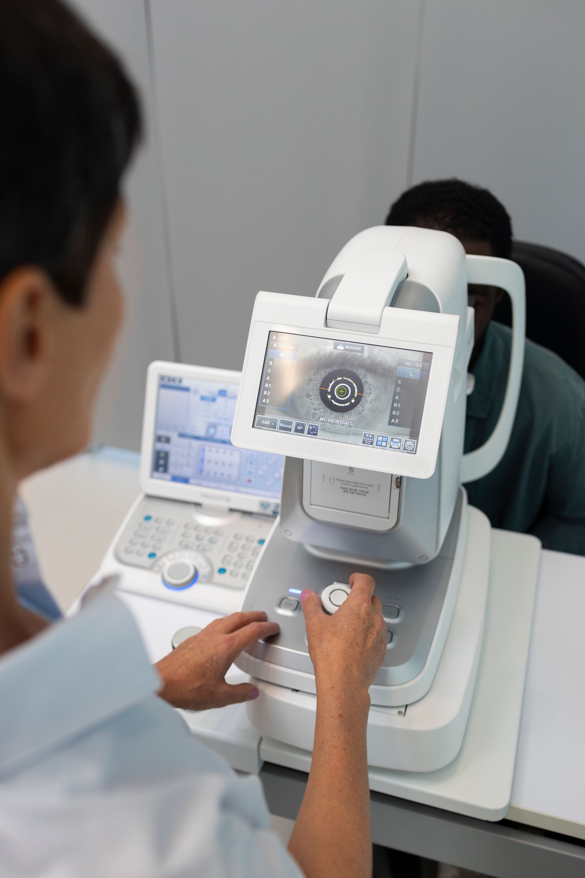 A woman is using a machine to check a man 's eye.