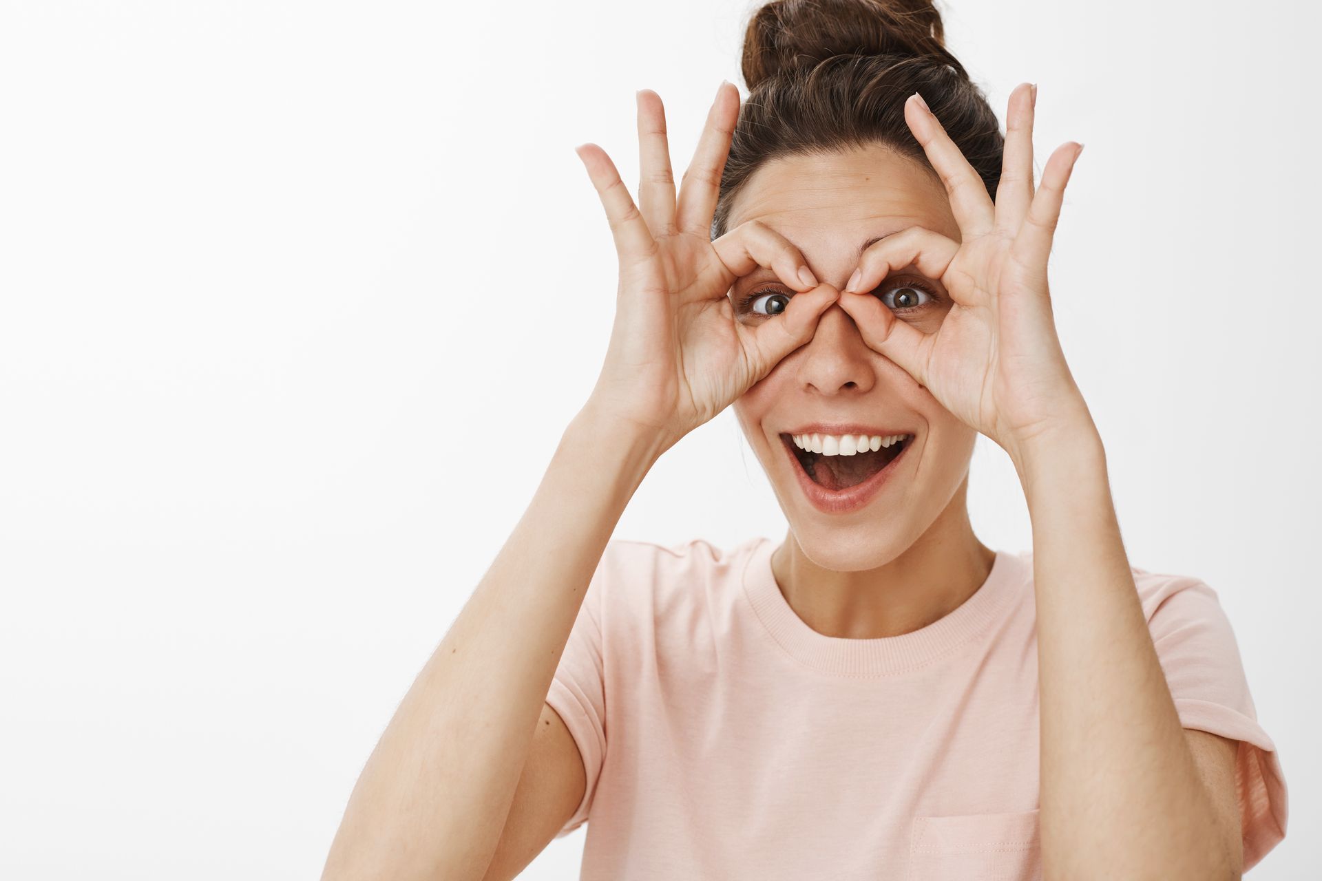 A woman is making a funny face by covering her eyes with her hands.