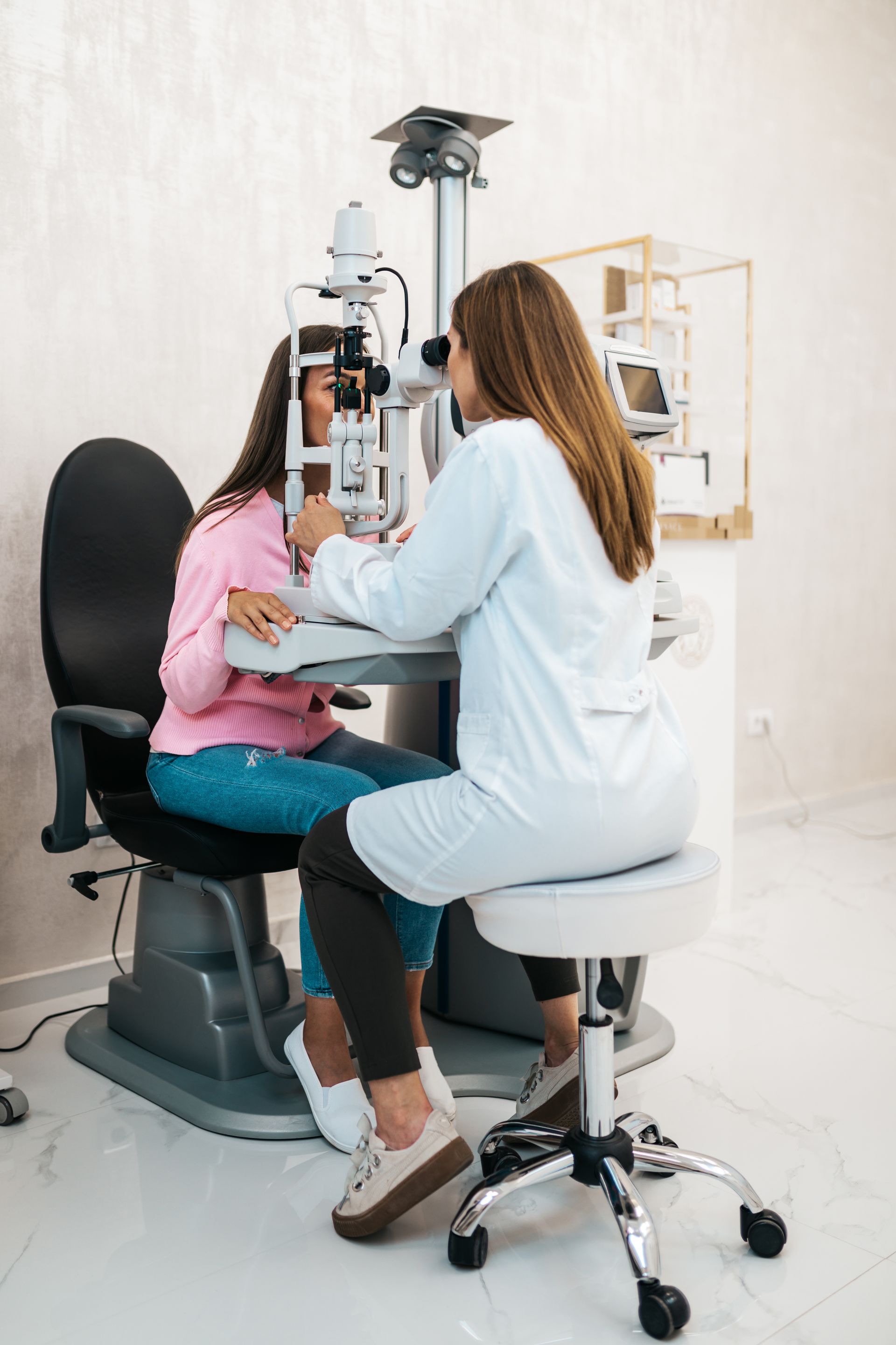 An ophthalmologist is examining a young girl 's eye.