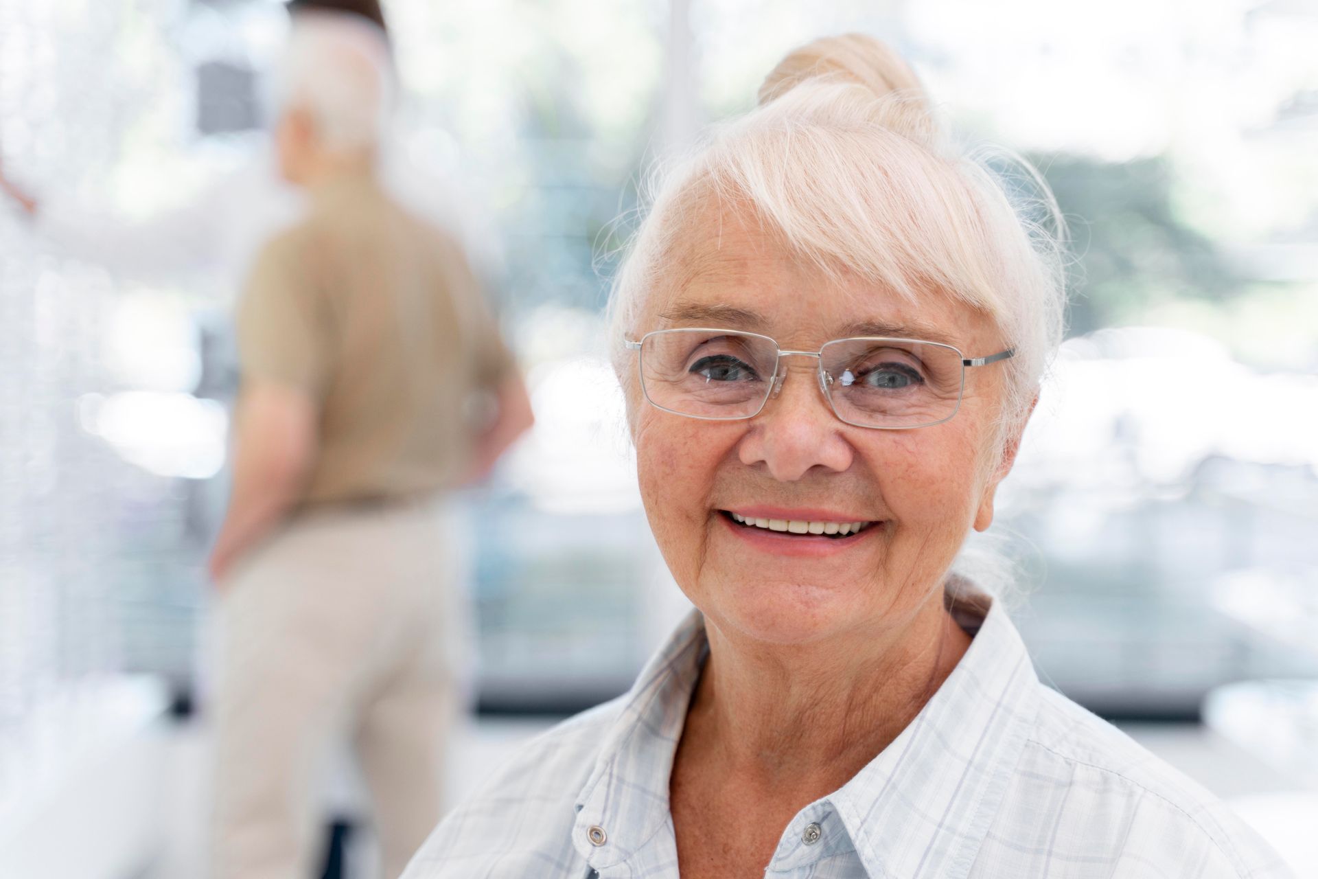 An elderly woman wearing glasses is smiling for the camera.