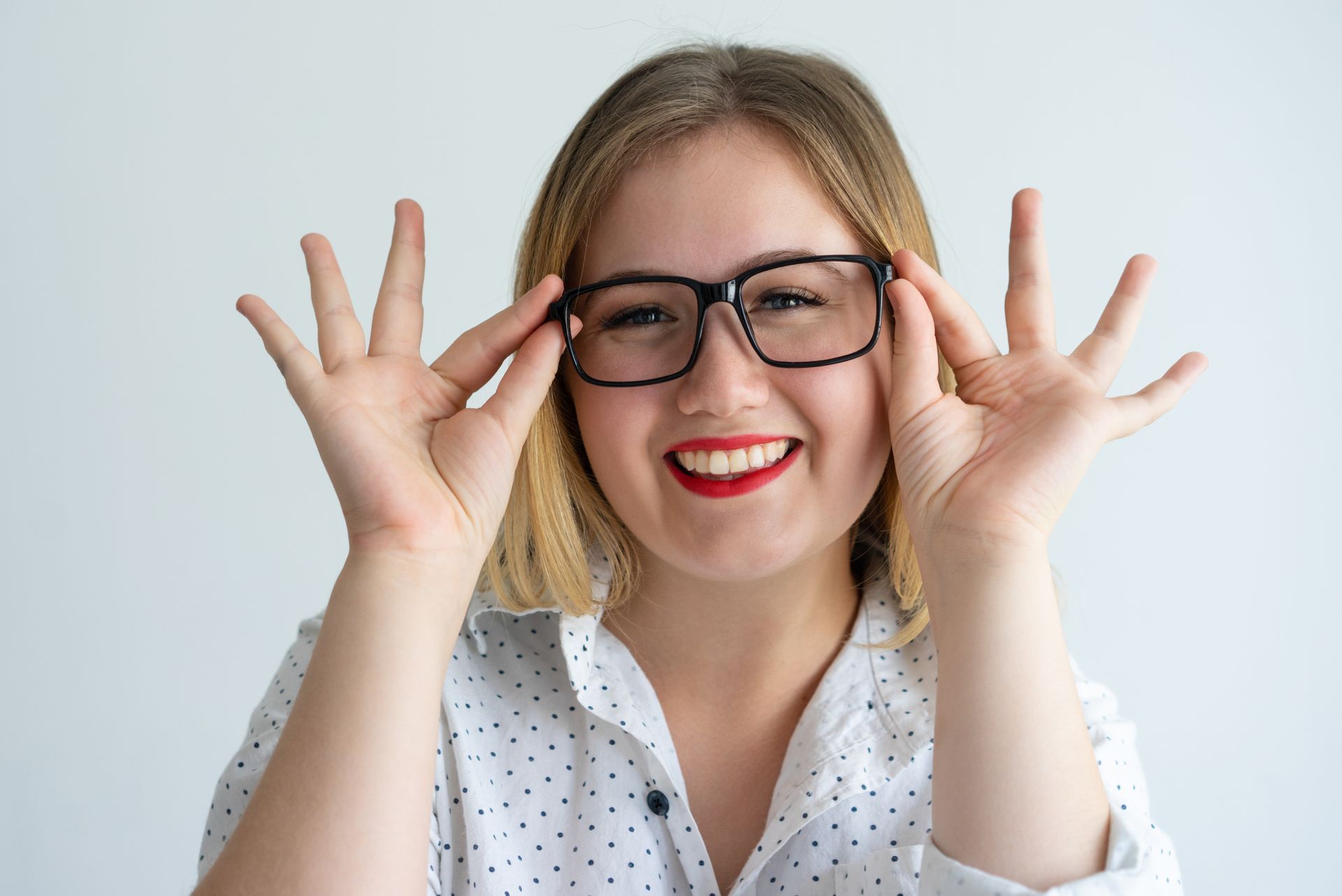 A woman wearing glasses is making a funny face with her hands.