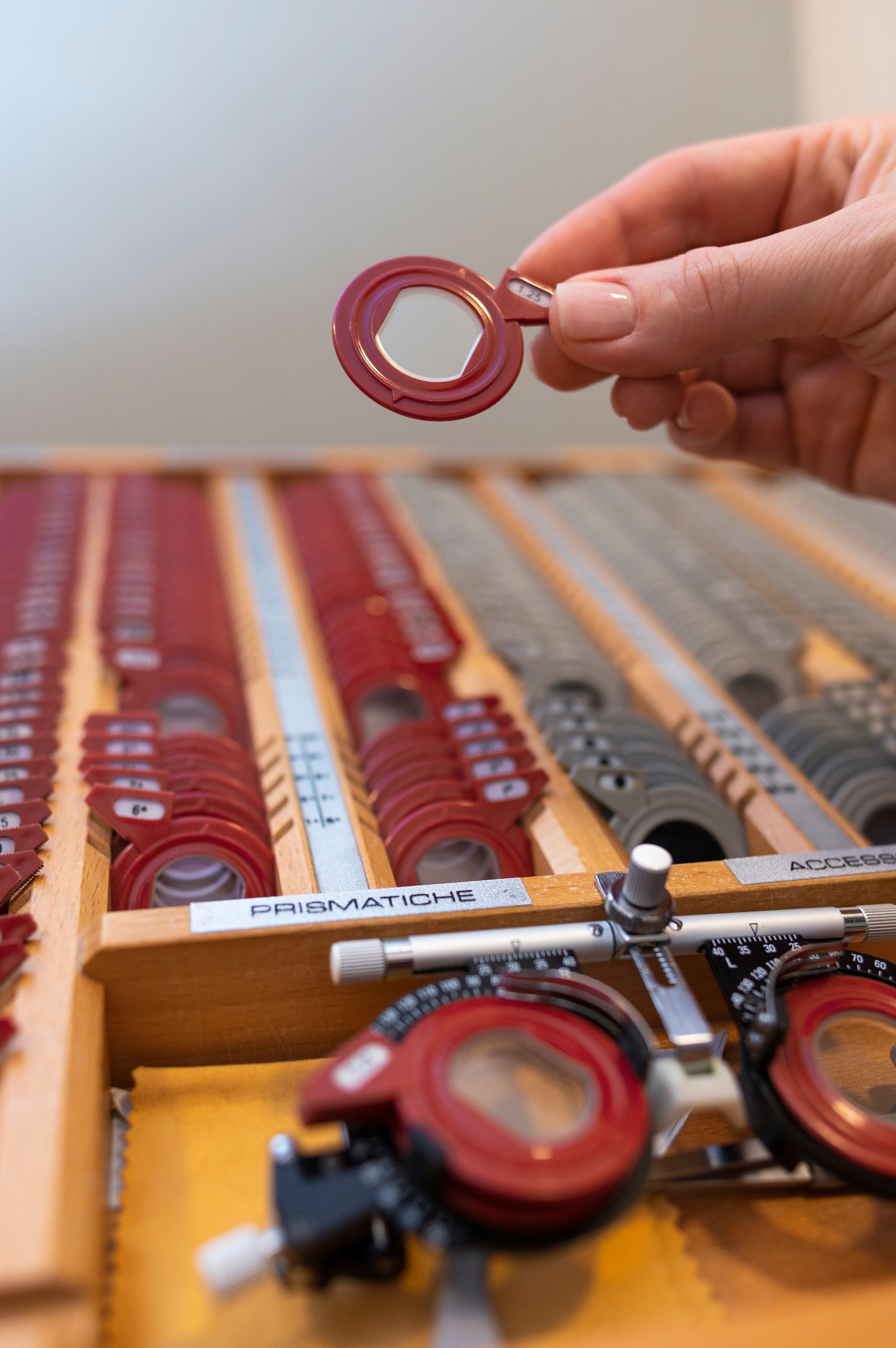 A person is holding a red object over a tray of glasses.