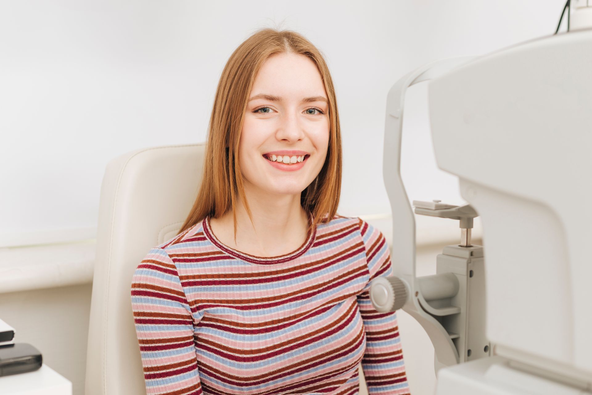 A woman is smiling while sitting in a chair in front of a machine.