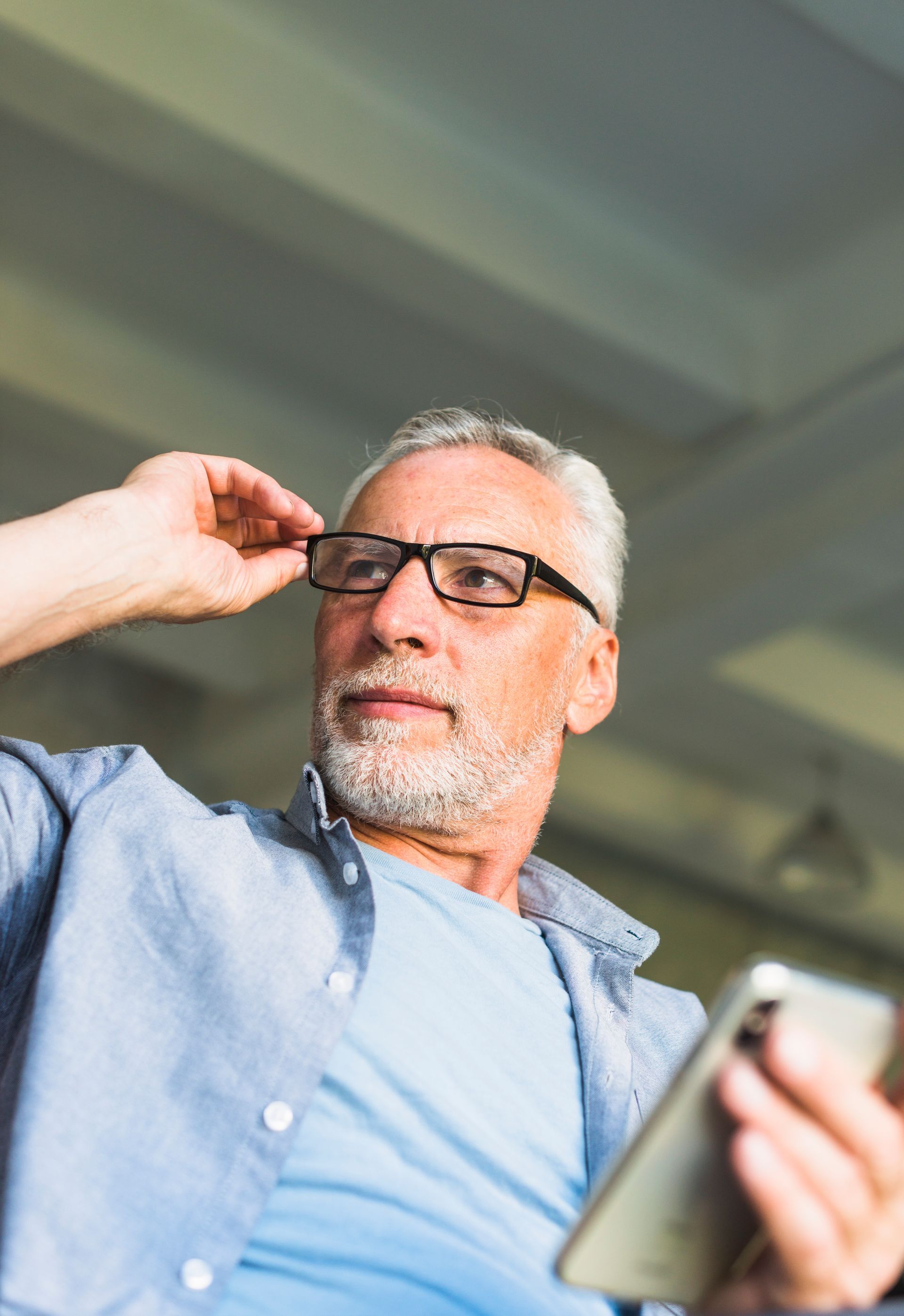 A man wearing glasses is holding a cell phone.