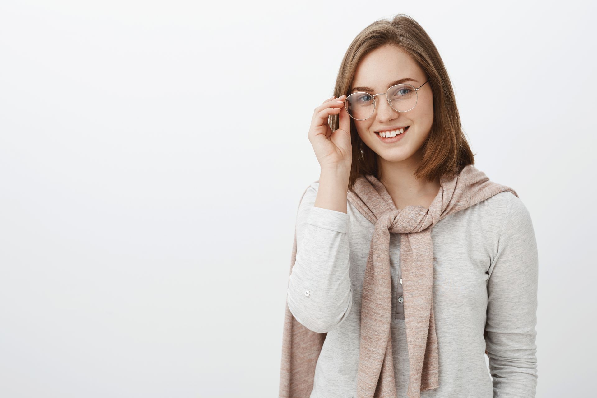 A young woman wearing glasses and a scarf is smiling.