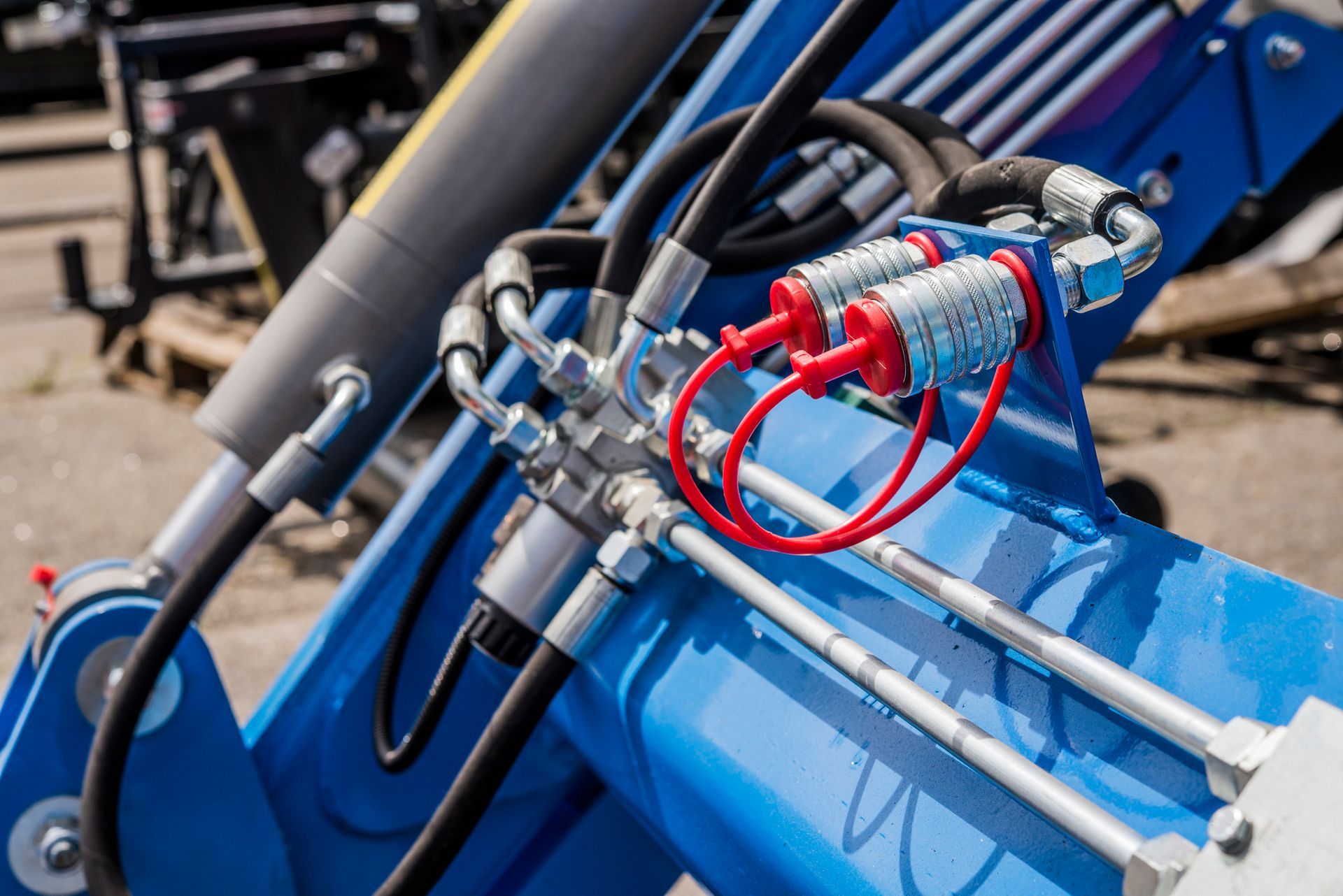 Blue hydraulic machinery with connected hoses and red caps.