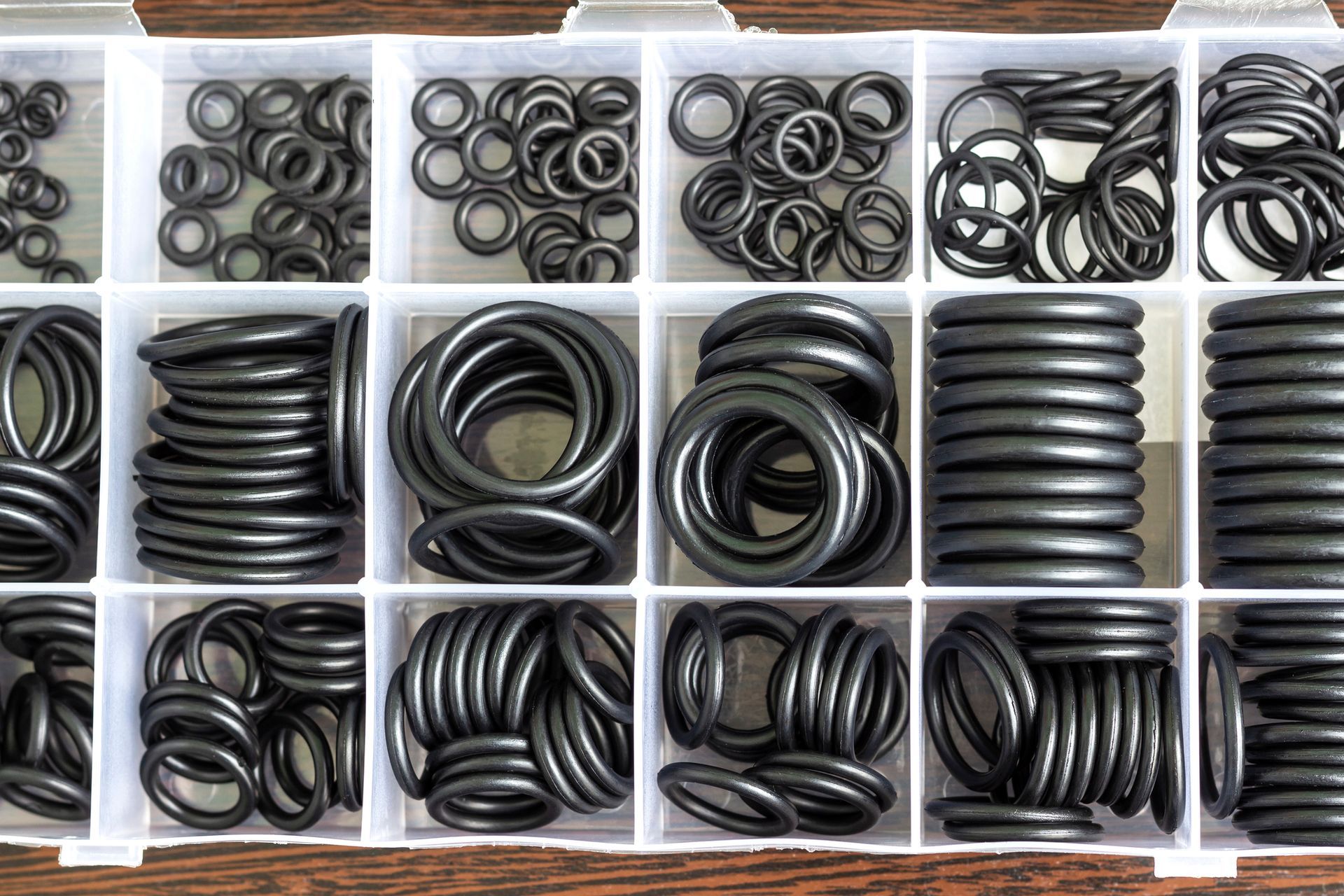 A box of assorted black rubber O-rings, organized in small compartments.