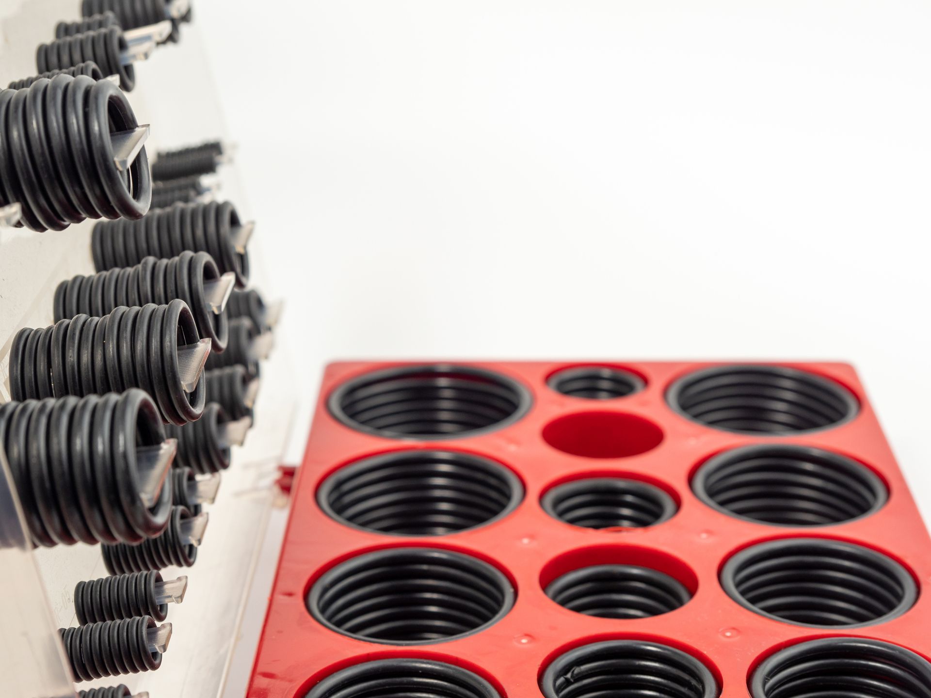 Black rubber O-rings arranged in a storage rack and a red organizer, likely for repair or maintenance use.