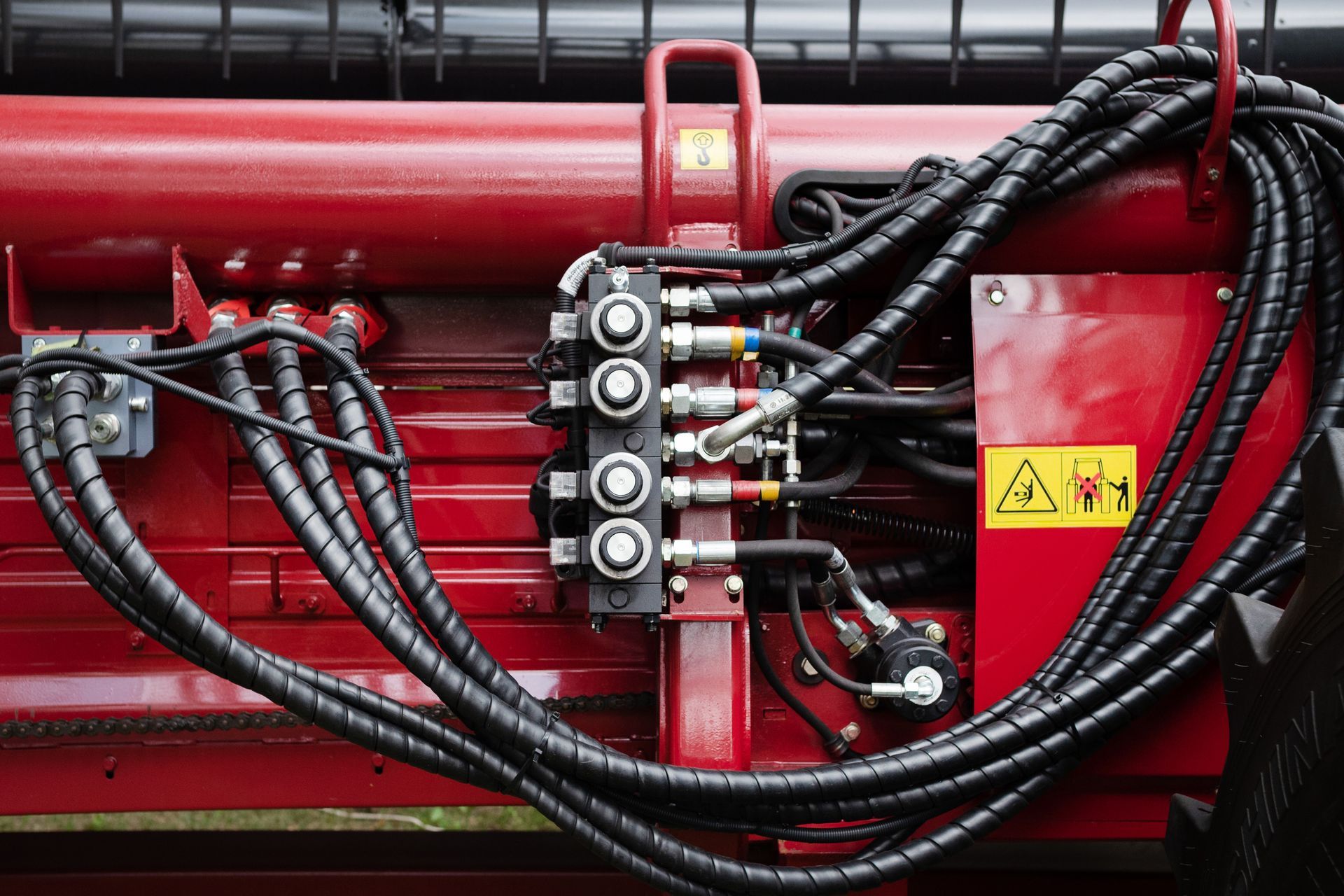 Red machinery with black hydraulic hoses and warning signs. Red machinery with black hydraulic hoses and warning signs.