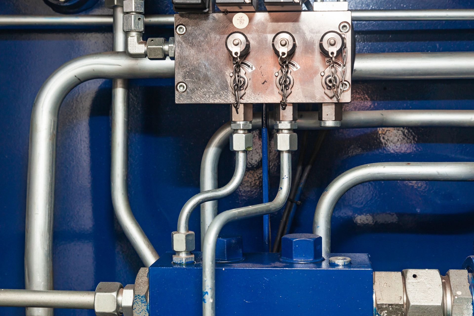 Close-up of industrial hydraulic equipment with shiny metal pipes and blue components.