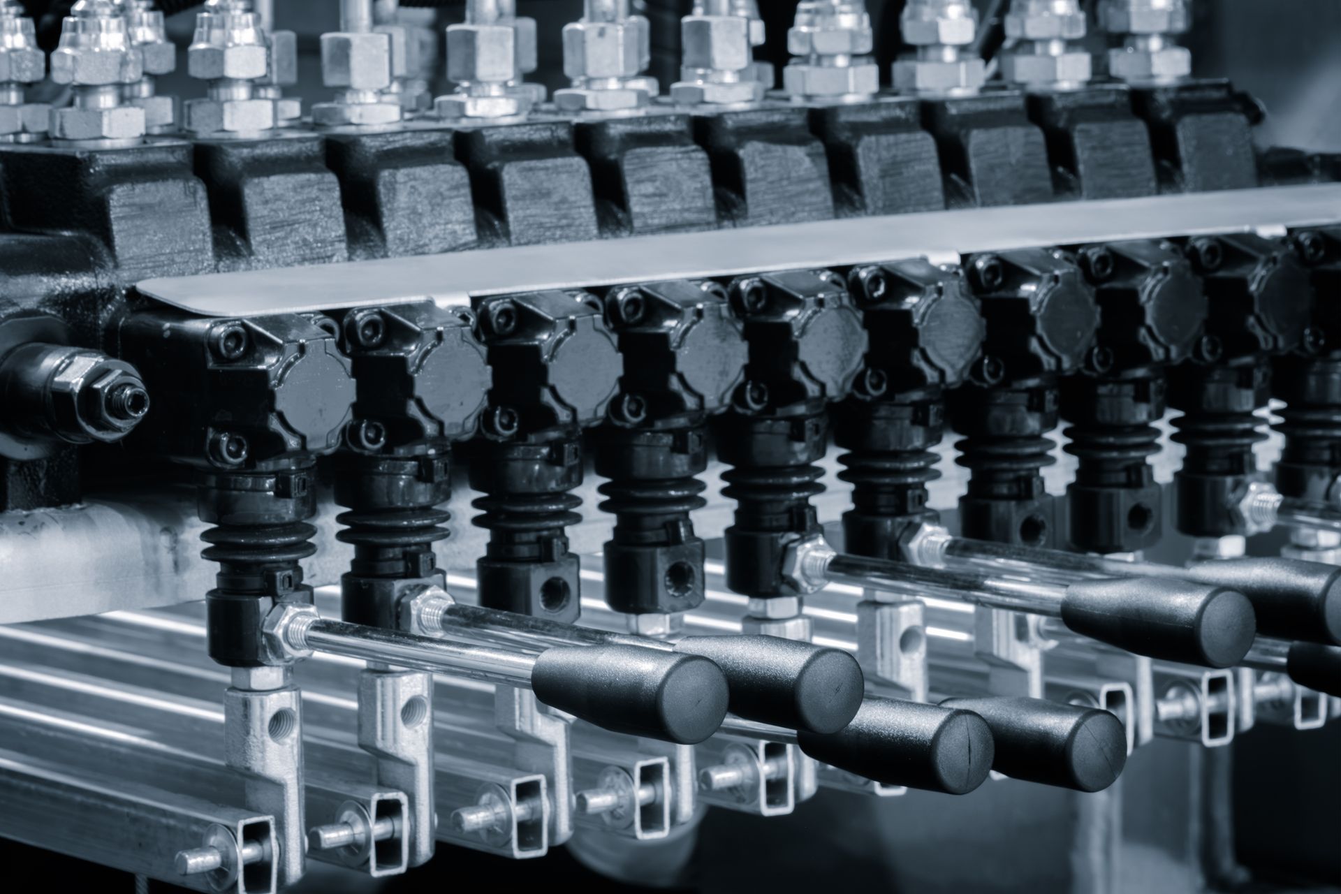 Close-up of a complex industrial machine with many nozzles and metallic components, possibly for fluid dispensing. Close-up of a complex industrial machine with many nozzles and metallic components, possibly for fluid dispensing.