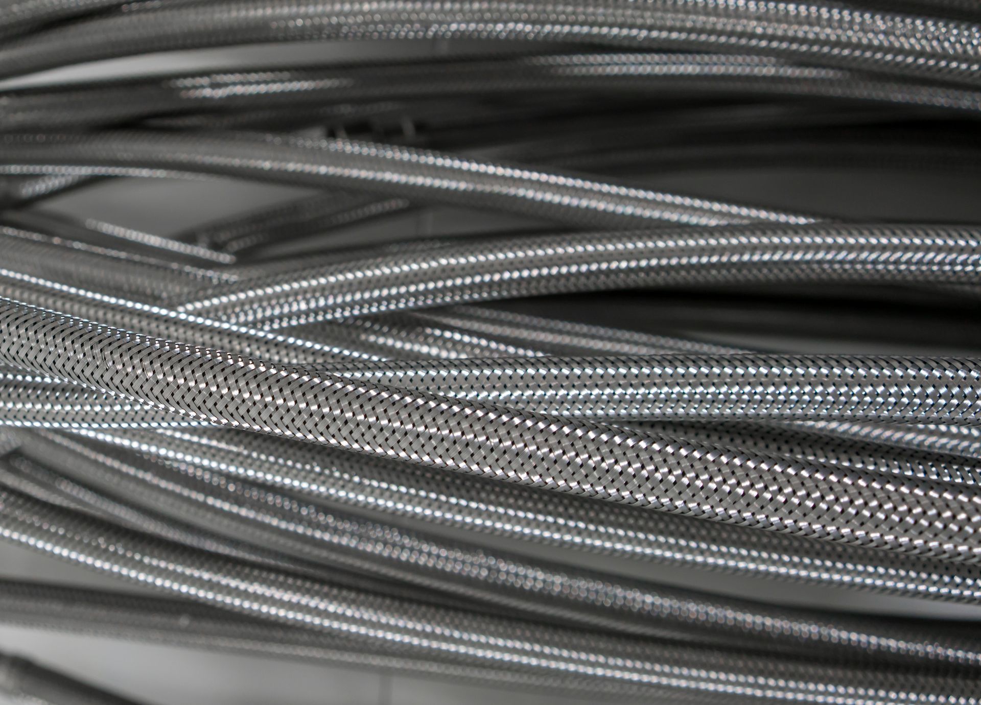 Close-up view of multiple flexible metal hoses, appearing silver and slightly shiny.