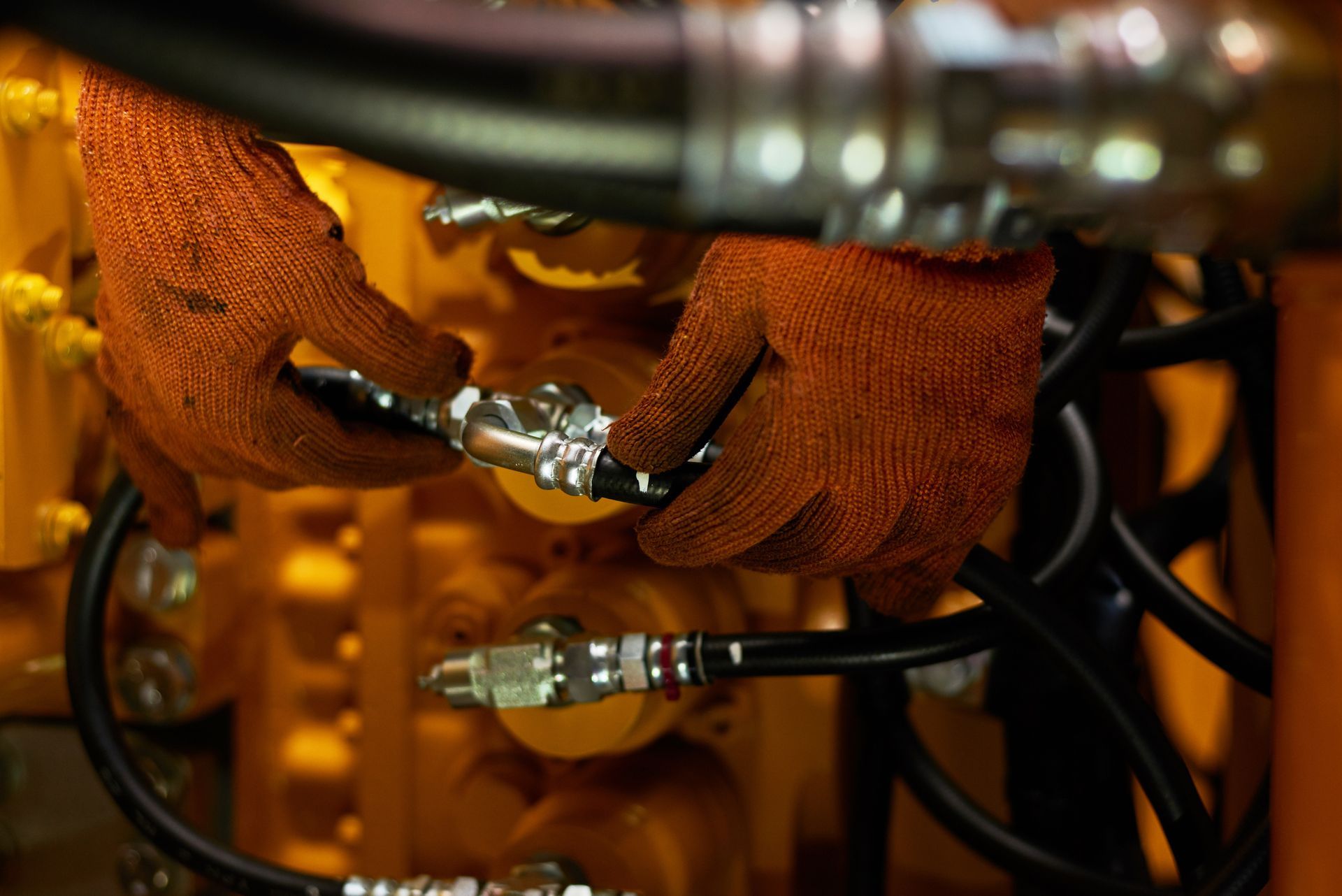 A technician repairing hydraulic pipes on a heavy industry machine.
