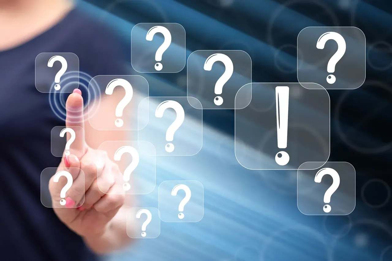 A person touches a digital interface displaying multiple floating question marks and one large exclamation point.