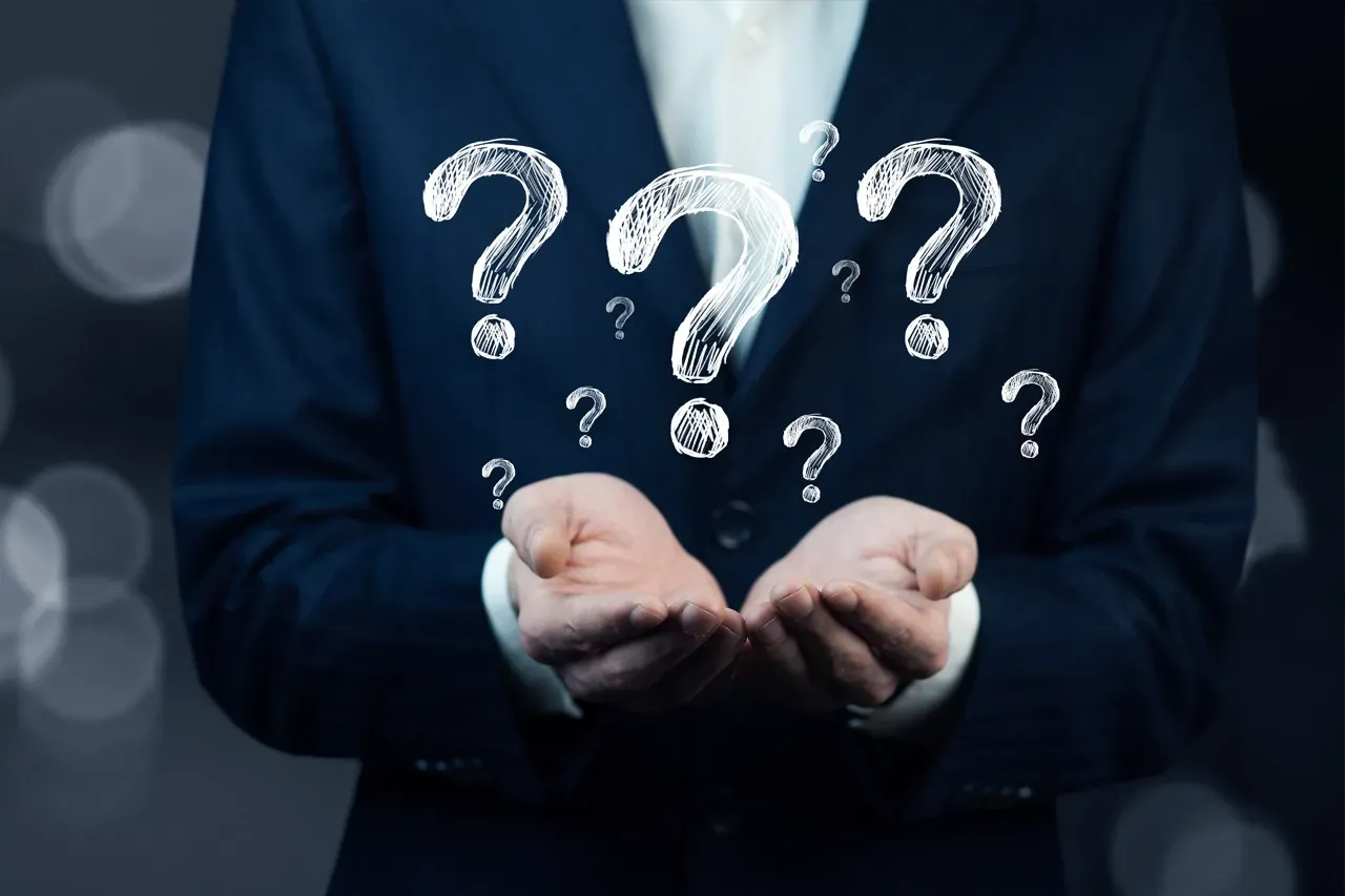 A person in a dark suit holds their hands open, with several glowing, white question marks floating above their palms.