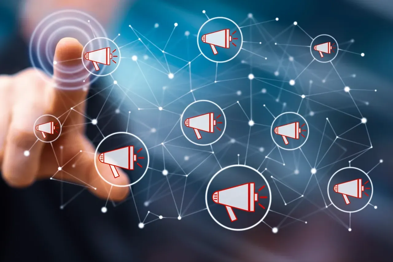 A hand reaches out to touch a glowing digital network of connected circles, each containing a red megaphone icon.