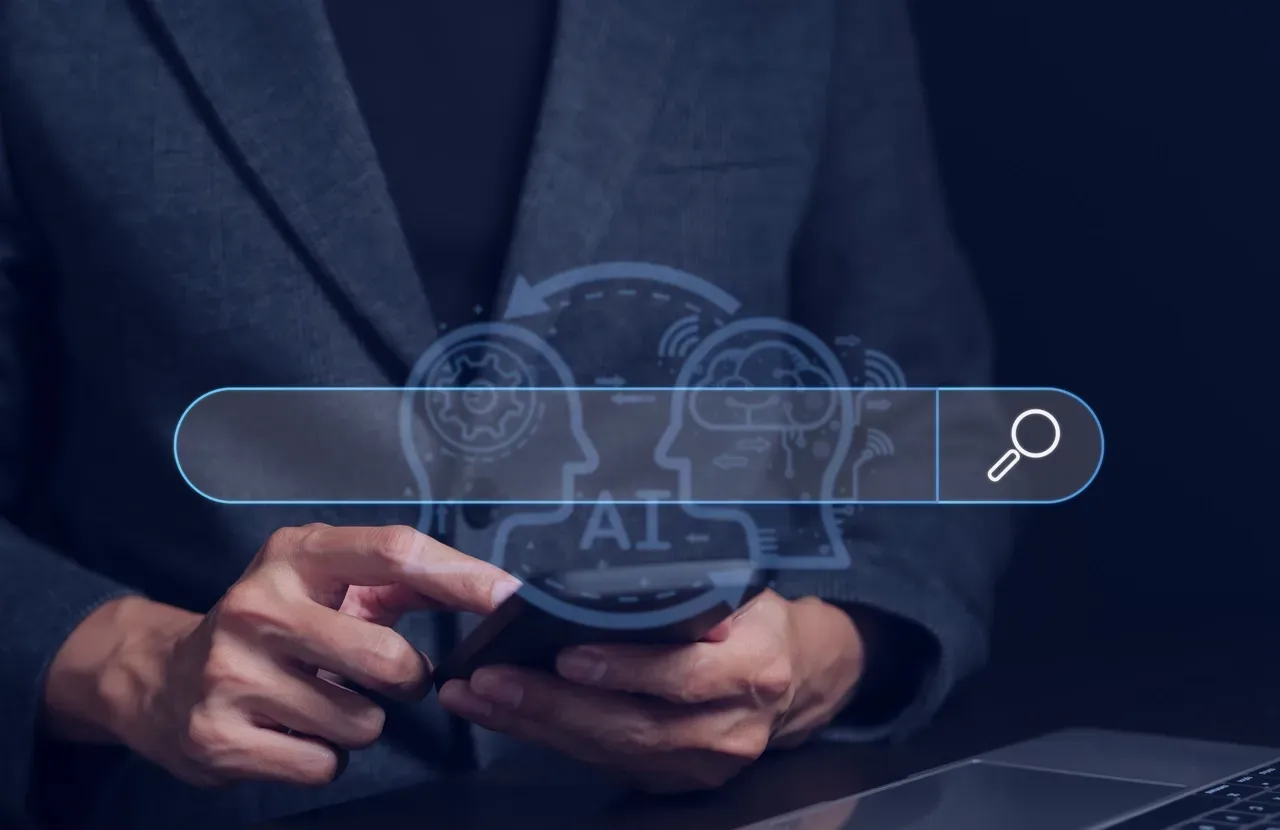 Person in a suit holding a smartphone, with a glowing AI search bar overlay featuring icons of a gear and a brain.