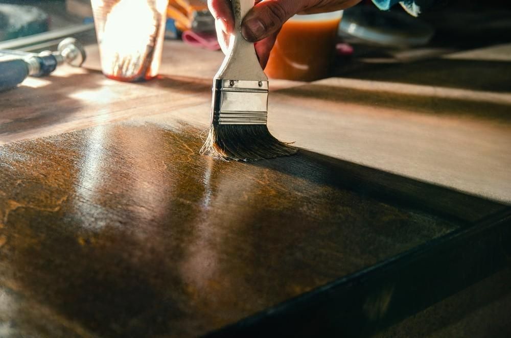 A person is painting a piece of wood with a brush.