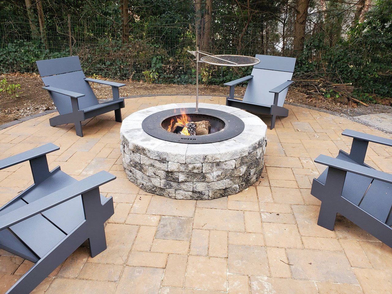 A fire pit is surrounded by chairs on a patio.