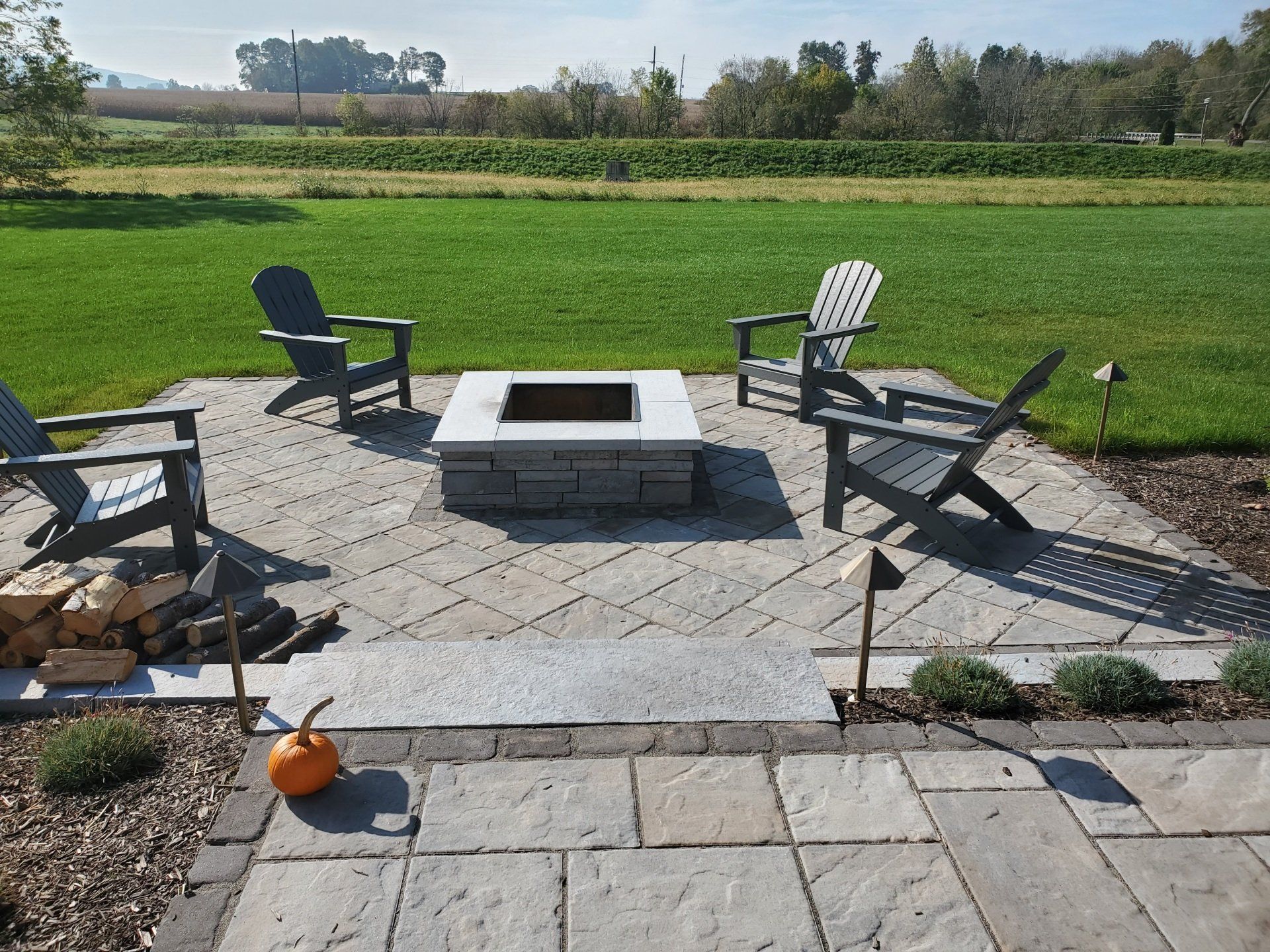 There is a fire pit in the middle of the patio with chairs around it.