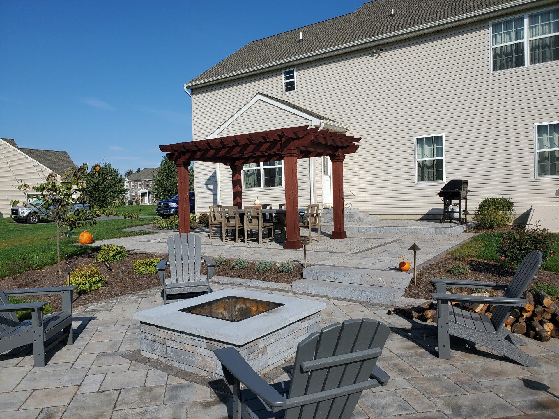 A patio with a fire pit and chairs in front of a house