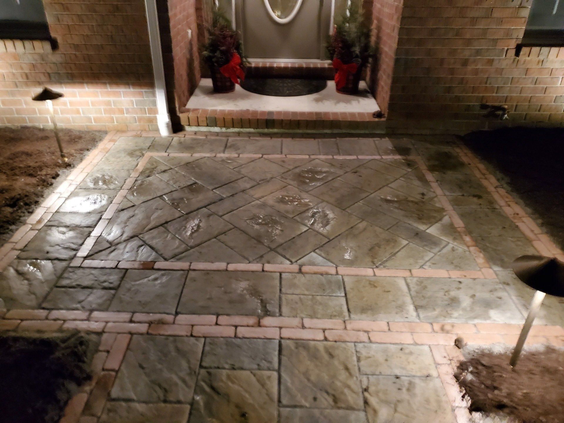 A brick walkway leading to the front door of a house at night.