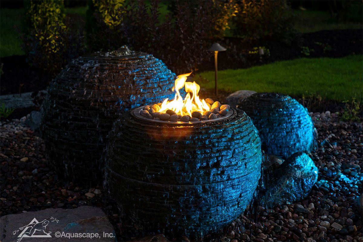 A fire pit is lit up at night in a garden.