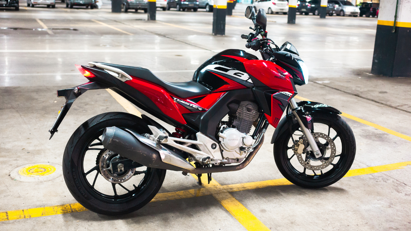 A red and black motorcycle is parked in a parking lot.