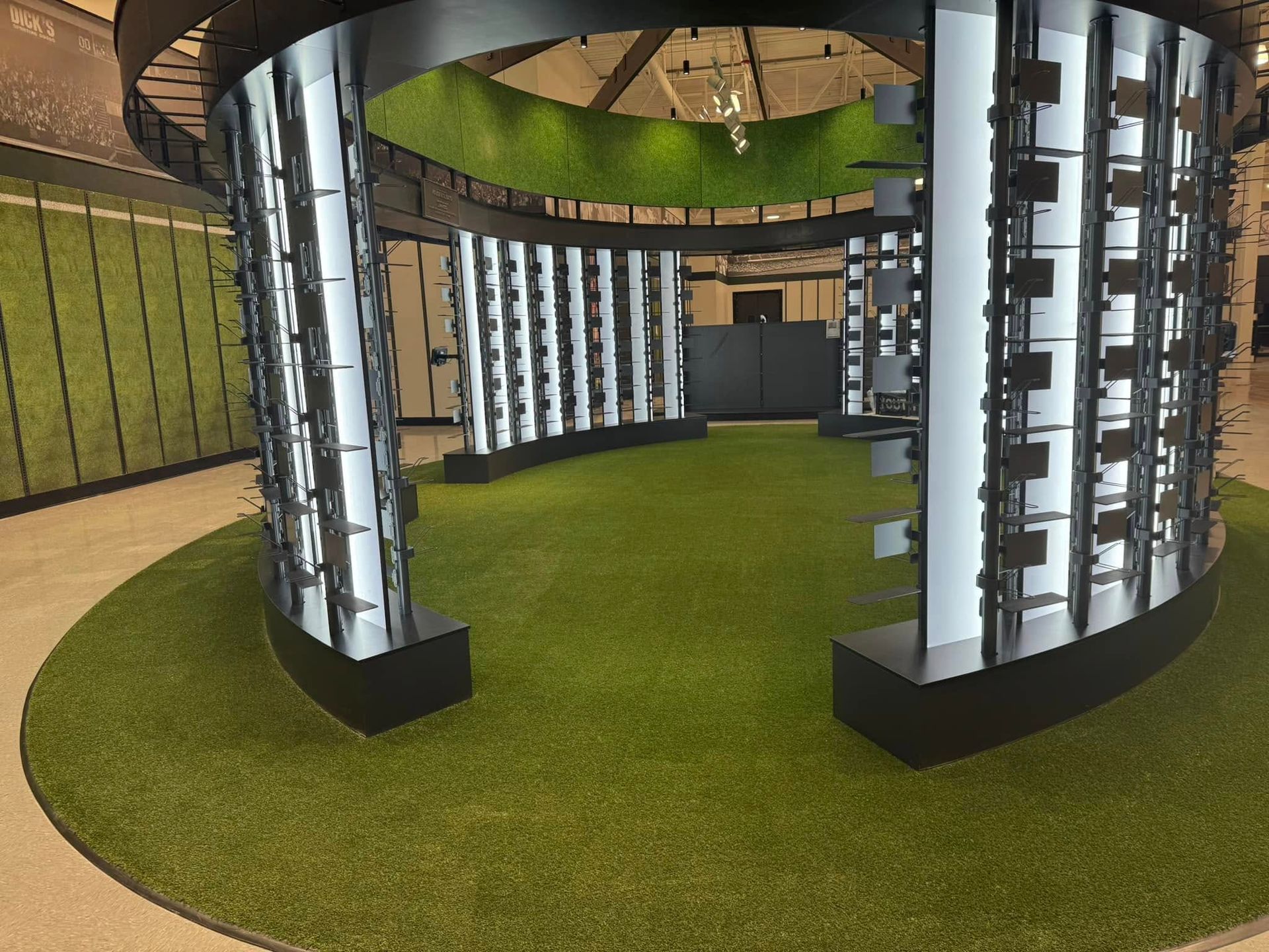 Circular display with eyewear on white panels, set in a grassy area. Black accents.