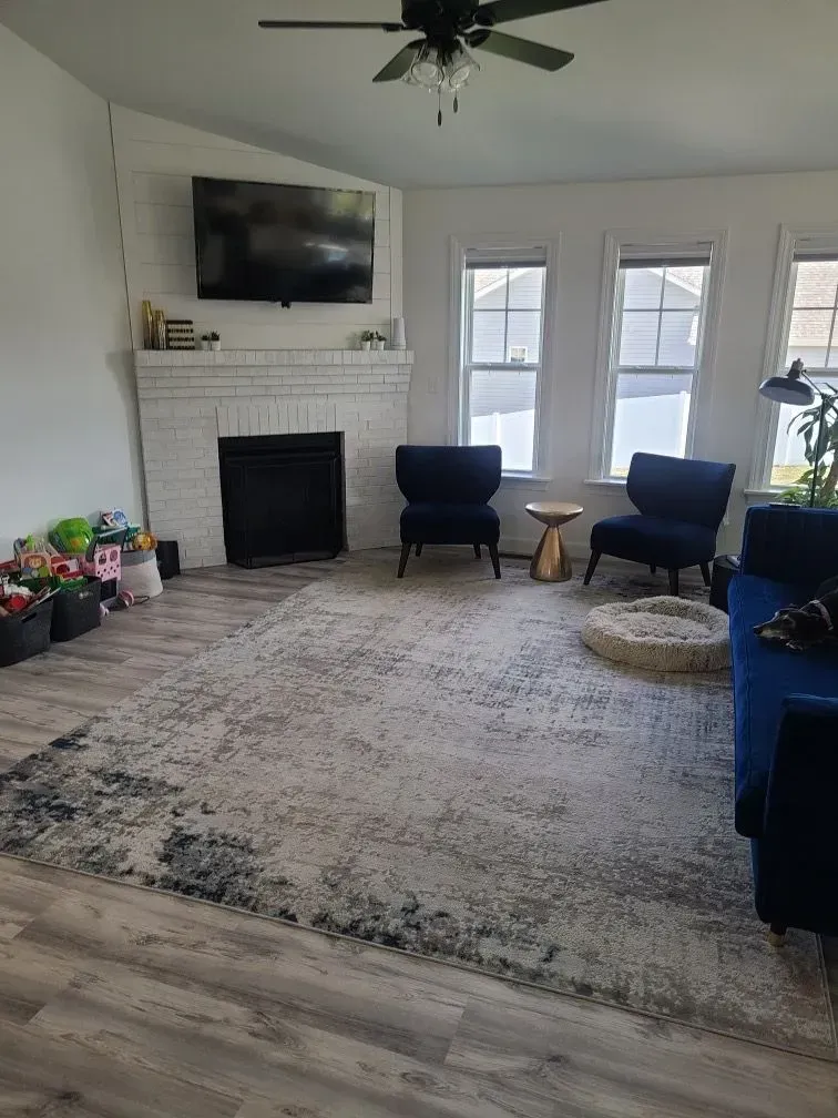 Living room with fireplace, TV, rug, furniture, and windows.