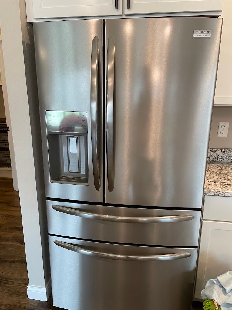 Stainless steel Frigidaire refrigerator with water dispenser and two lower freezer drawers.