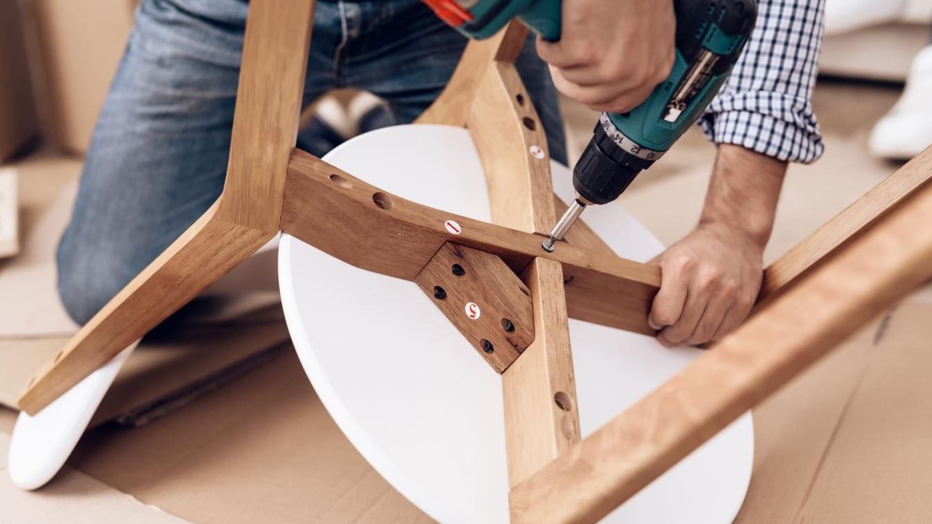 A man is using a drill to assemble a table - Toronto Furniture assembler