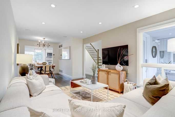 A living room with a couch , coffee table , television and stairs.