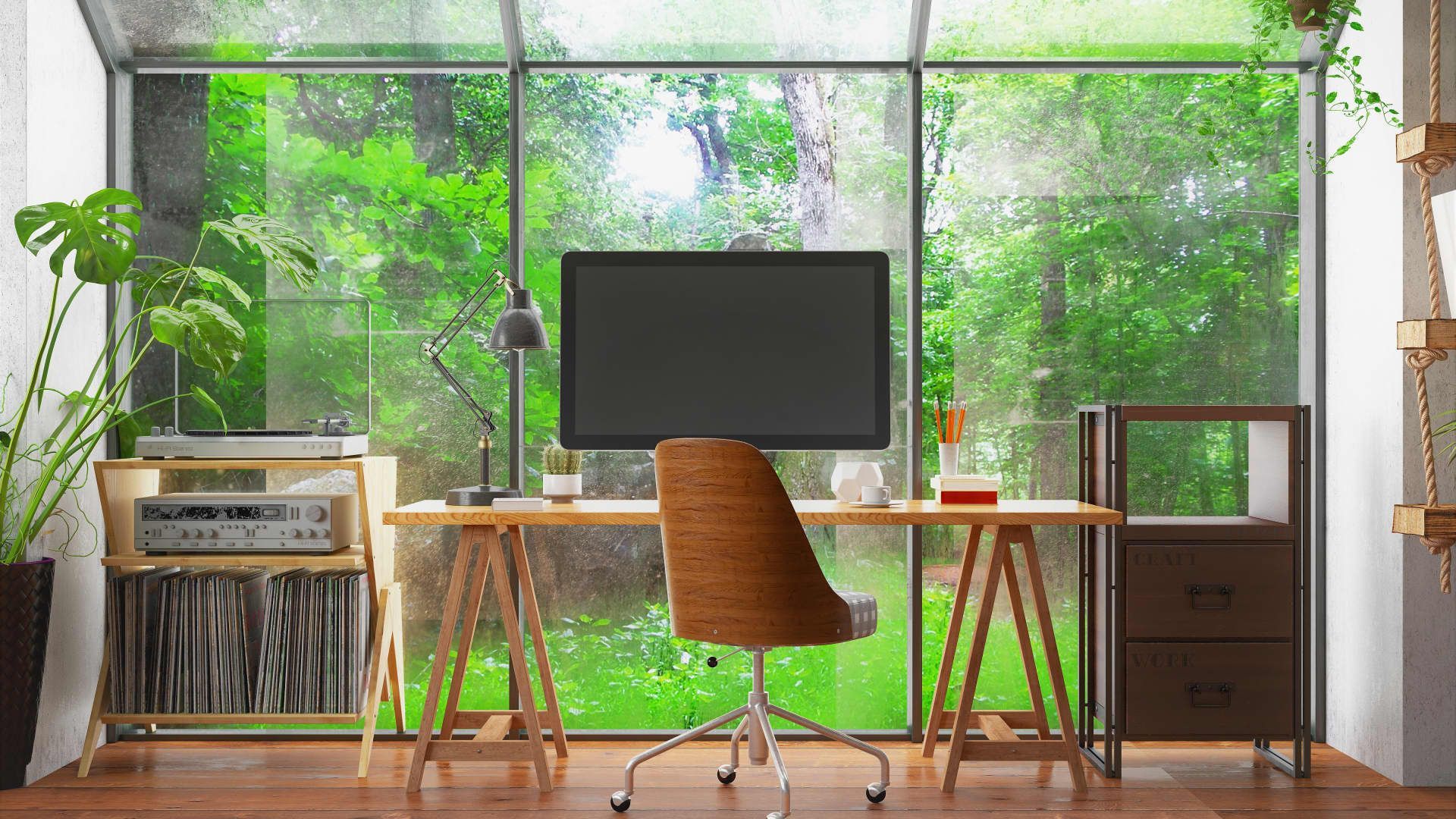 A desk with a computer and a chair in front of a large window.