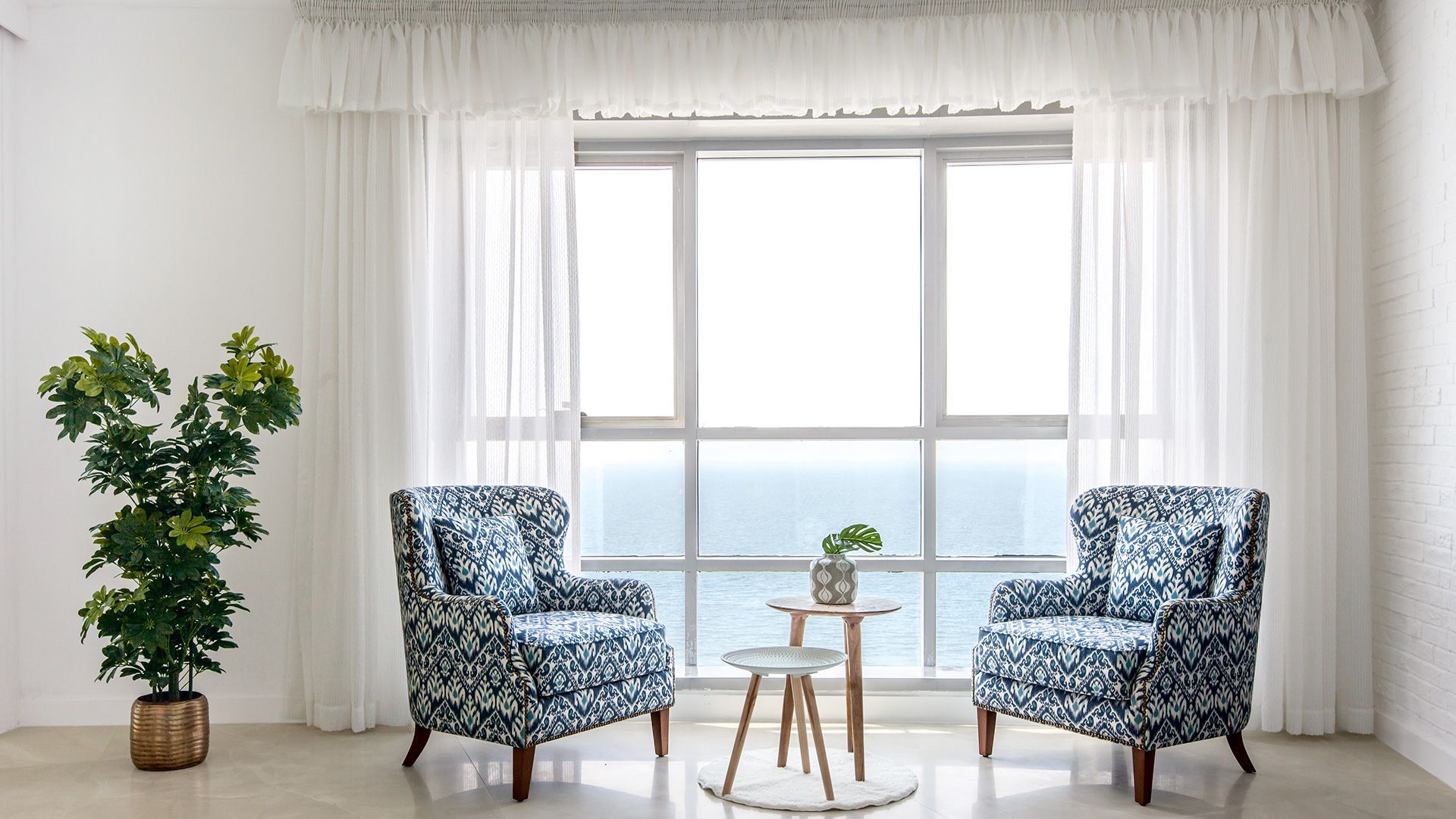 A living room with two chairs and a table in front of a large window