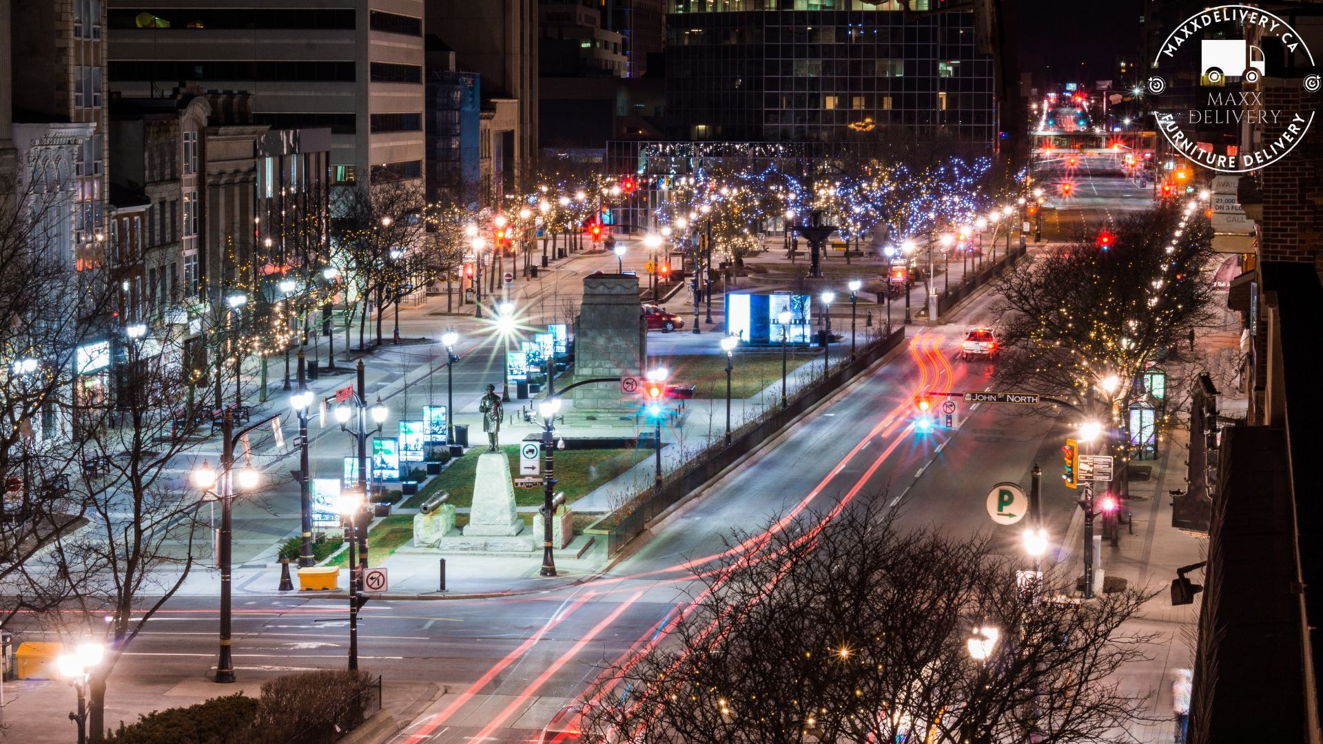 An aerial view of a city street at night with a parking sign in the foreground