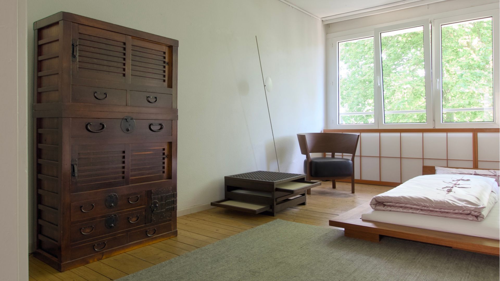 A bedroom with a bed a chair and a dresser