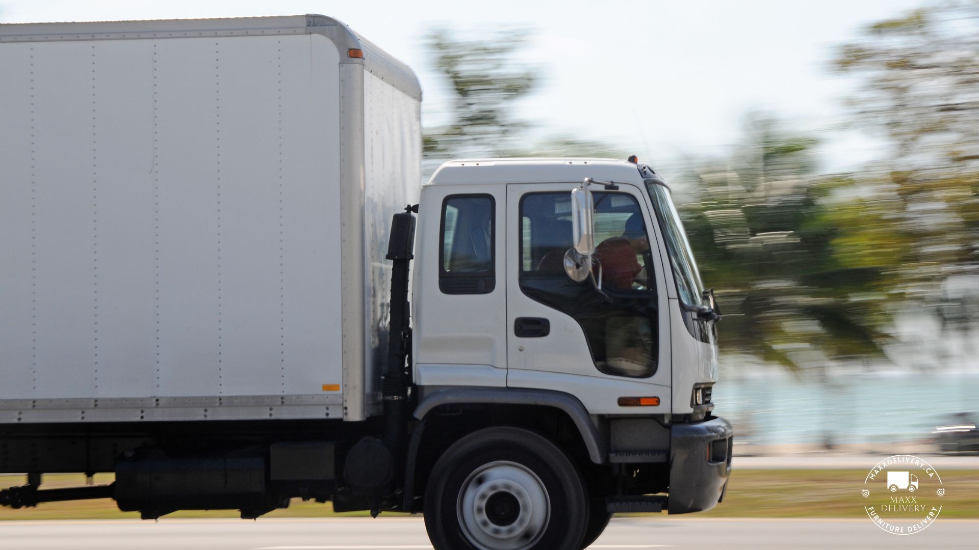 A white box truck is driving down the road