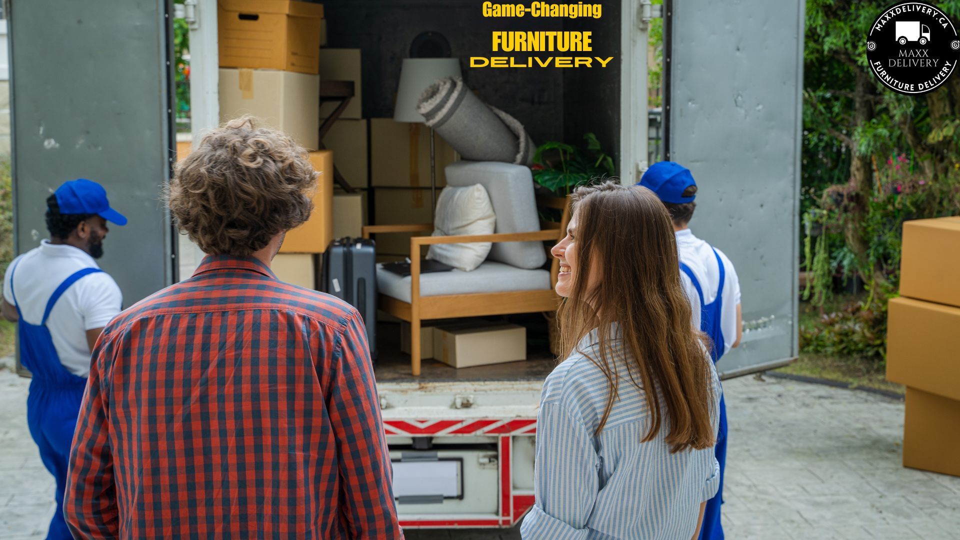 A man and a woman are standing in front of a furniture delivery truck