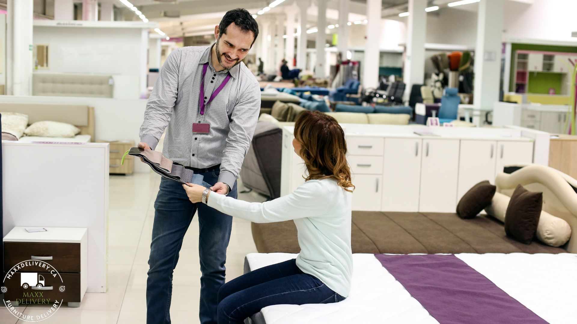 A man is helping a woman choose a mattress in a store